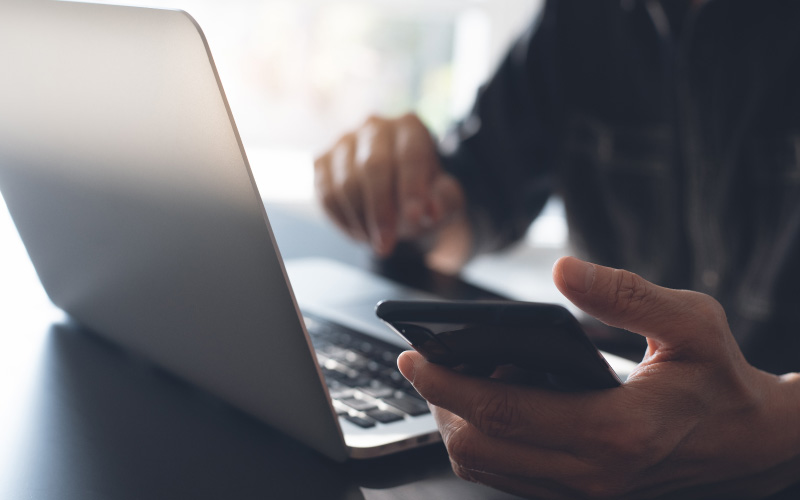 Person browsing phone and laptop