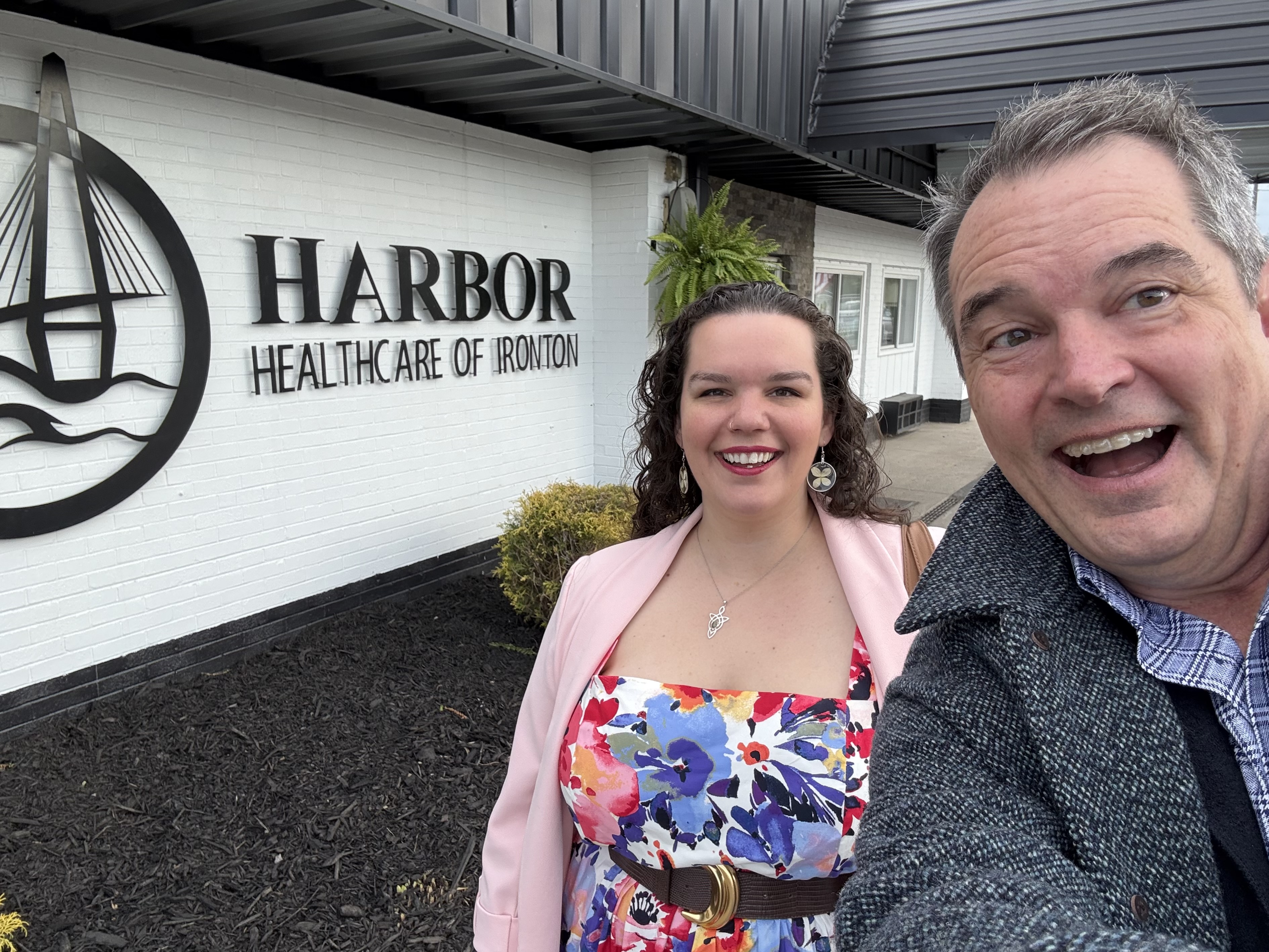 Eric Gibson and Skye Johnson smiling outside the Harbor Healthcare building