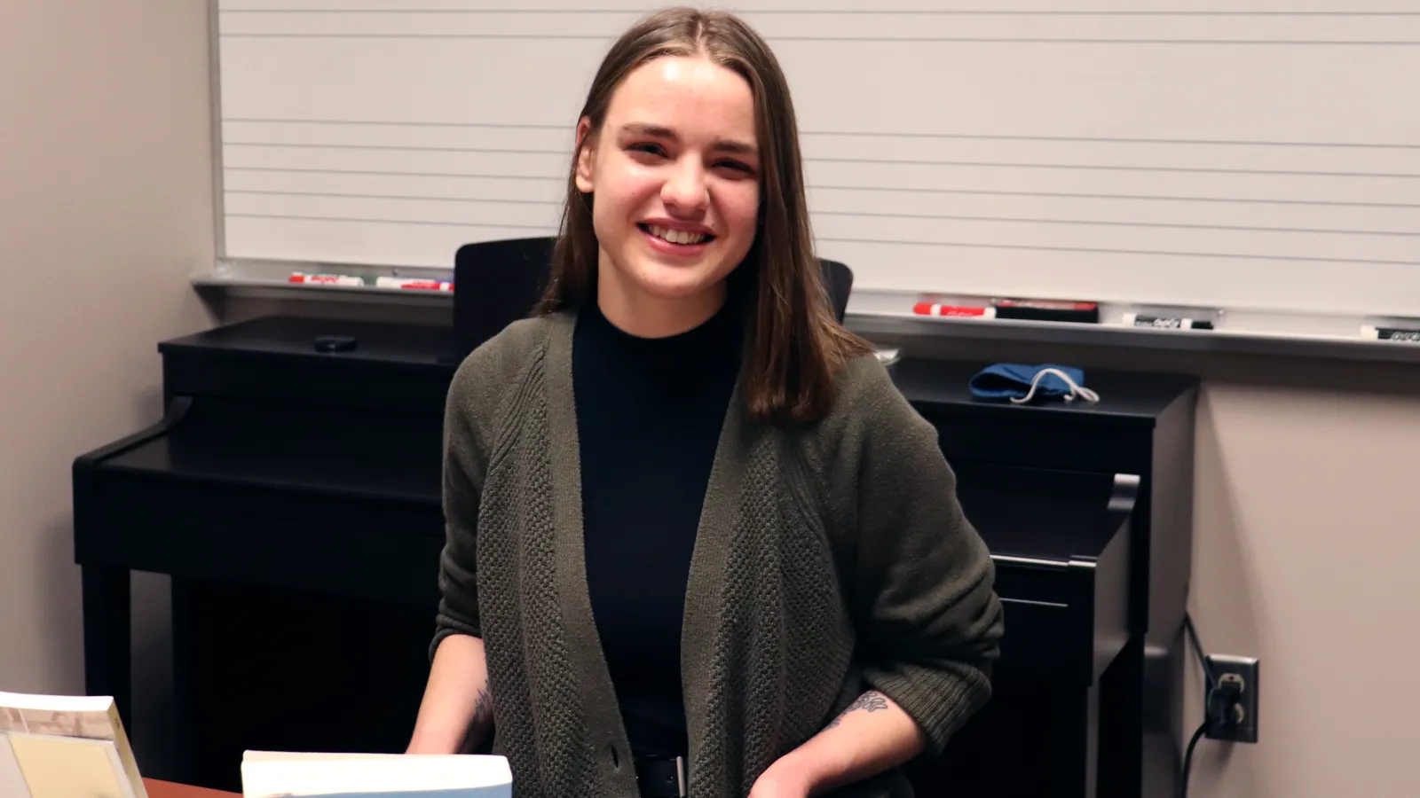Heidi Bowles sitting at desk with books and piano in the background