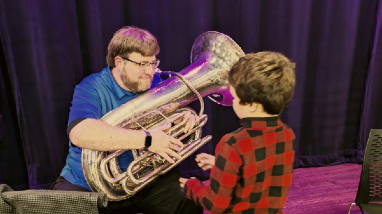 Tuba player introducing young student to the instrument
