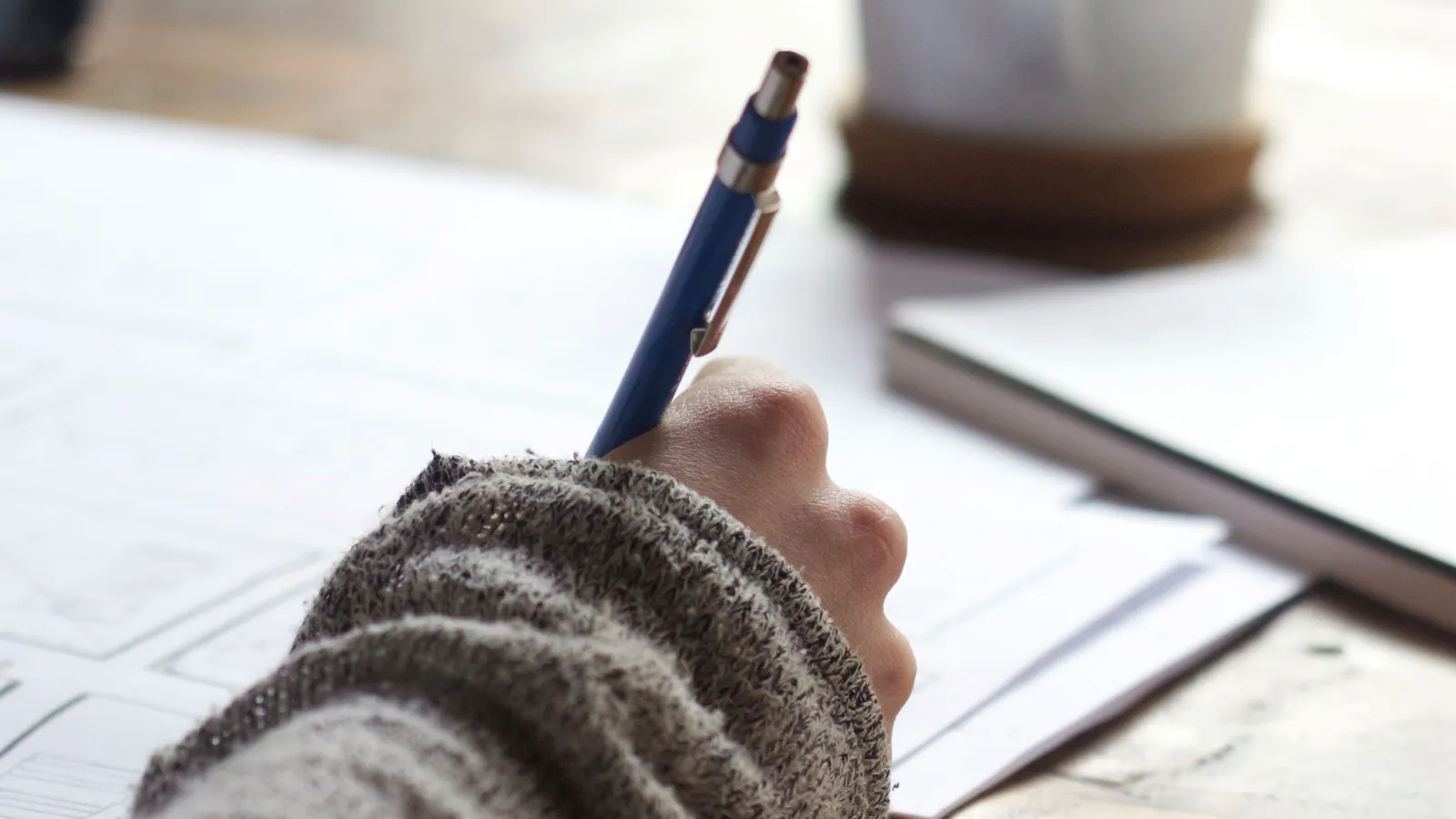 A student writing. Photo: Green Chameleon on Unsplash
