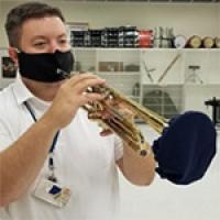 Trumpet player using instrument mask and bell cover