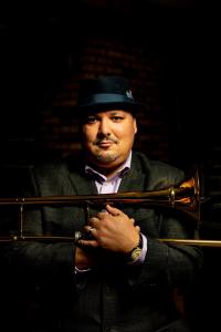 Michael Dease wearing a hat, holding his trombone