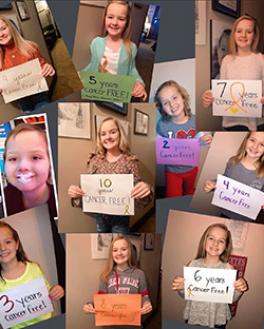 Smiling children holding "cancer free" signs