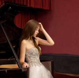 Picture of piano teacher standing in front of piano