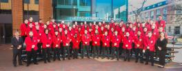 Men's Glee Club in scarlet blazers posed on riders on the plaza outside the music building