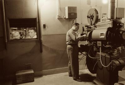 Man working with projector in movie theater 1958 Man working with projector in movie theater 1958