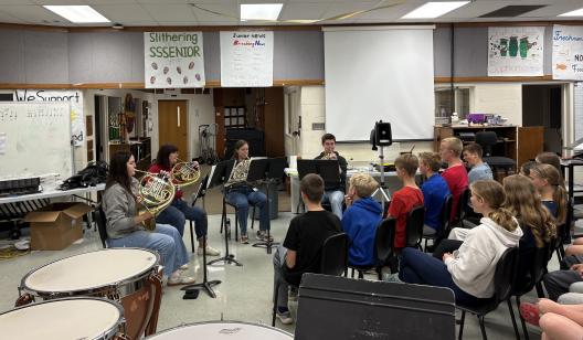 Horn quartet performing in school classroom for a student audience