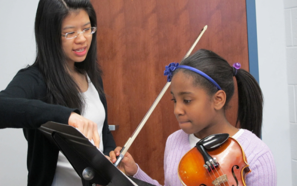 College student giving violin lesson to young student
