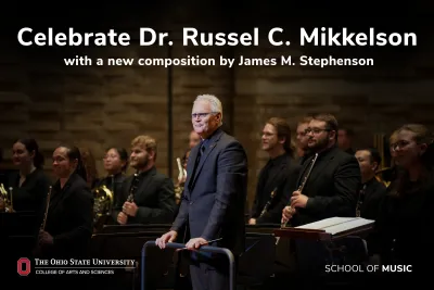 Russell Mikkelson standing at podium in front of band members