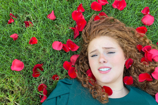 Girl lying on grass strewn with rose petals