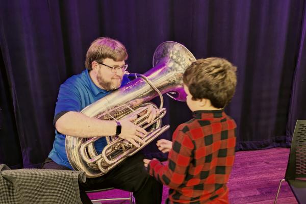 Tuba player introducing young student to the instrument