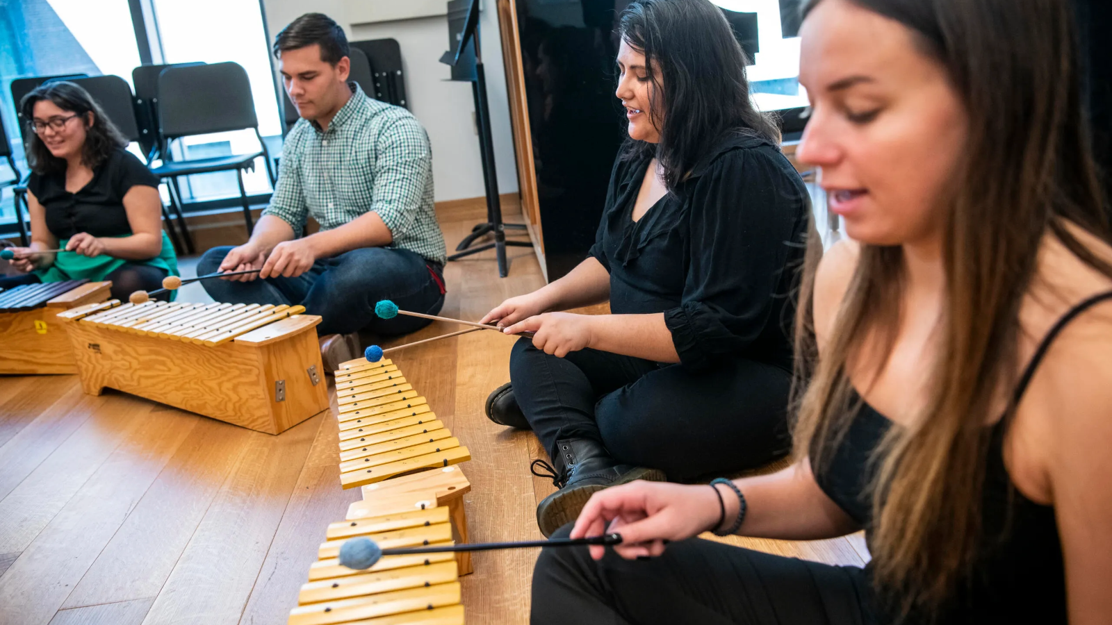 Students sitting the the floor playing xylophones