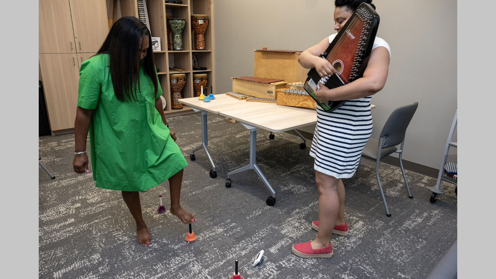 Therapist plays autoharp while patient plays foot bells in instrument room